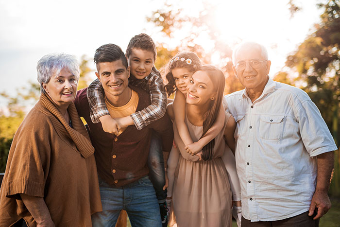 family with kids and grandparents smiling for photo together wearing fall colors