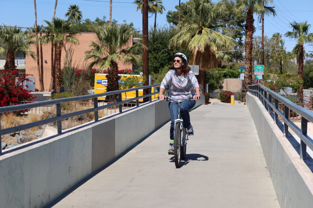 Woman Riding a Bicycle on a Bridge in Palm Springs, California, Riding Toward the Camera with Palm Trees in the Background