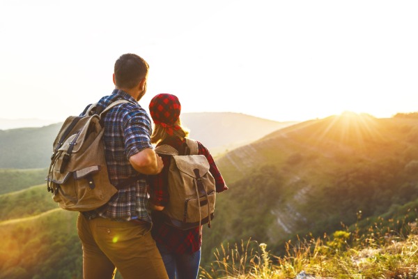 couple standing at the top of a mountain after hiking at sunset