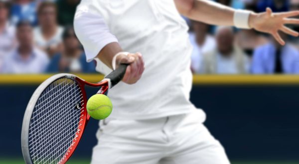 tennis player holding racket hitting tennis ball